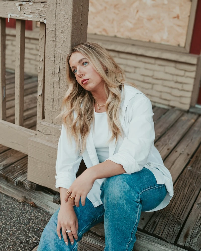 woman sitting outside on her front decking, looking lost in thought 